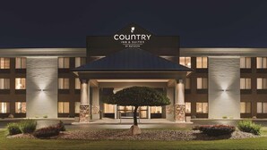 A Country Inn & Suites building with a prominent entrance, a covered patio area, and a landscaped front yard. - Country Inn & Suites by Radisson, Mt. Pleasant-Racine West, WI (Mount Pleasant)