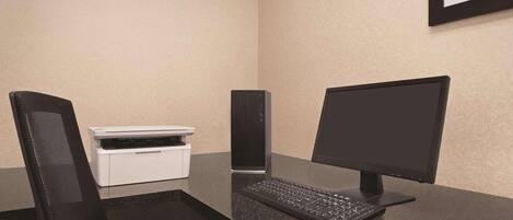 A modern office setup with a desktop computer, keyboard, mouse, and a printer on a glass desk.