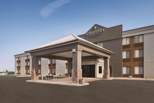 Edificio de Country Inn & Suites con un porche cubierto, varios pisos y un estacionamiento.
