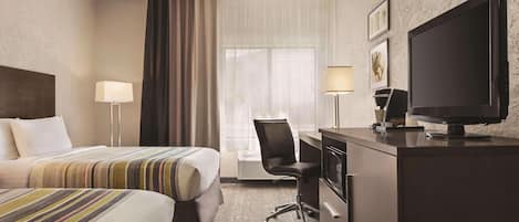 A hotel room with two beds, a desk with a chair, a television, and a window with curtains.