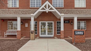 A brick building with a white entrance, a bench, and a 'Lobby' sign.