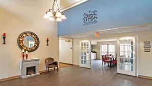 A spacious room with a fireplace, a dining area with red chairs, and a large mirror on the wall.