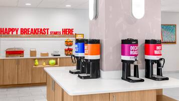 Una barra de desayuno con máquinas de café y un cartel que dice 'HAPPY BREAKFAST STARTS HERE'.