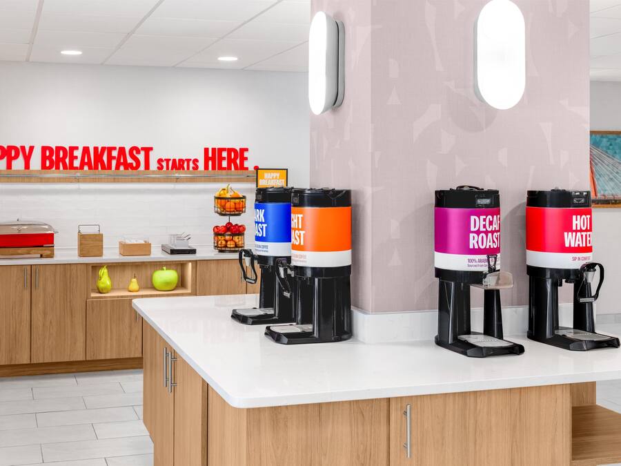 Un bar à petit-déjeuner équipé de machines à café et d’une pancarte sur laquelle on peut lire : « C’EST ICI QUE COMMENCE UN EXCELLENT PETIT-DÉJEUNER. »