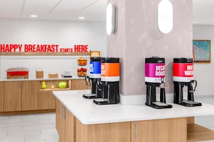 Una barra de desayuno con máquinas de café y un cartel que dice 'HAPPY BREAKFAST STARTS HERE'.