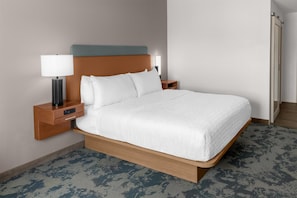 Una habitación de hotel con una cama, una mesita de noche, una lámpara y una luz en la pared.