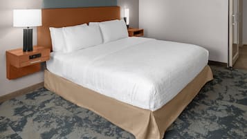 A hotel room with a large bed, two bedside tables with lamps, a wooden headboard, and a patterned carpet.