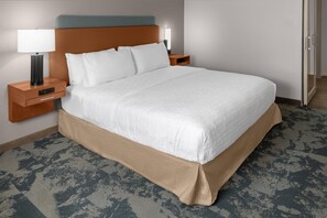 Ein Hotelzimmer mit einem großen Bett, zwei Nachttischen mit Lampen, einem Holz-Kopfteil und einem gemusterten Teppich.