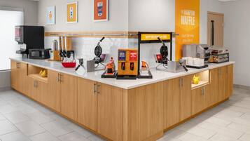 Un área de cocina moderna con cafetera, máquina para hacer gofres y diversos electrodomésticos.