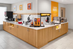 Un área de cocina moderna con cafetera, máquina para hacer gofres y diversos electrodomésticos.