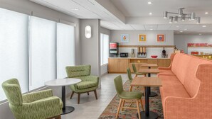 Un espace repas moderne avec des chaises à revêtement vert, une table ronde et un canapé.