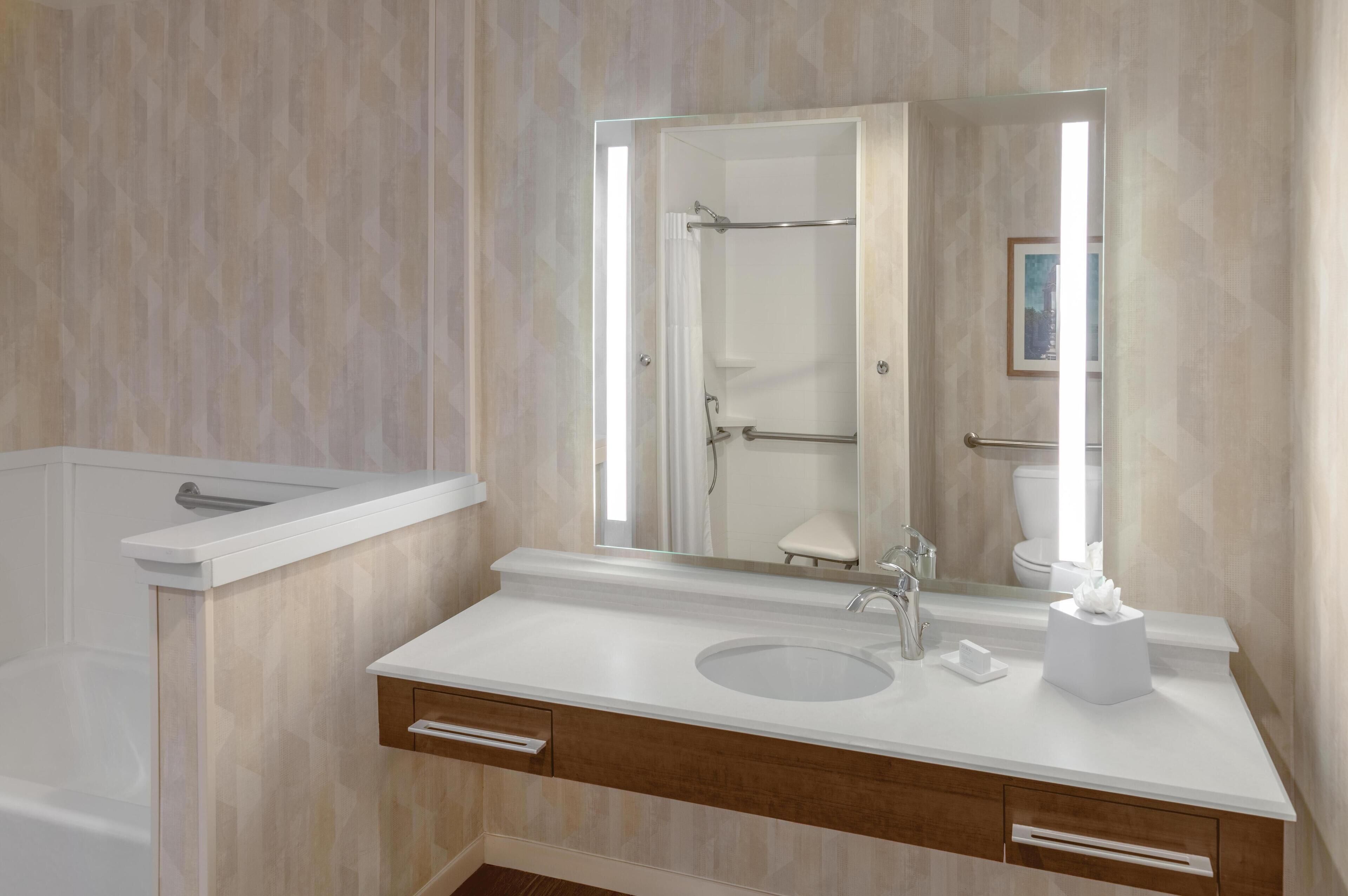 A modern bathroom with a bathtub, a sink, and a large mirror.