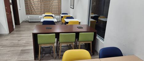 A conference room with a wooden table, green and yellow chairs, and a large window.