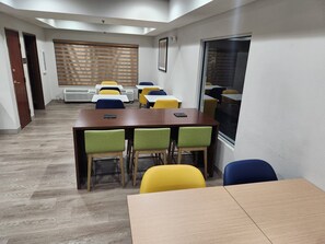 A conference room with a wooden table, green and yellow chairs, and a large window.