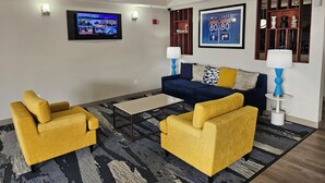 A living room with a blue sofa, yellow armchairs, a coffee table, and a TV displaying 'NEWS MIX'.