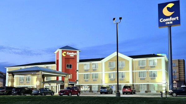 A Comfort Inn hotel with a red and beige building, multiple parking spaces, and a clear sky.