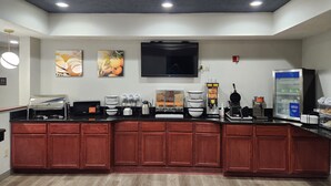 A modern kitchen area with a coffee station, microwave, toaster, and a refrigerator.