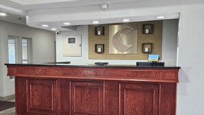 A reception desk with a wooden finish, a large wall-mounted sign, and a digital display.