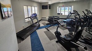 A gym with treadmills, elliptical machines, and weight benches.