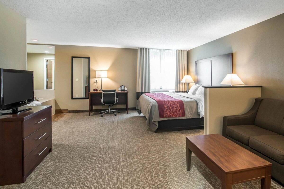 A hotel room with a bed, a desk, a television, a sofa, and a coffee table.