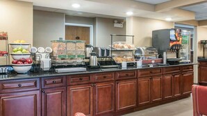 A buffet area with various food items, a coffee machine, and a refrigerator.