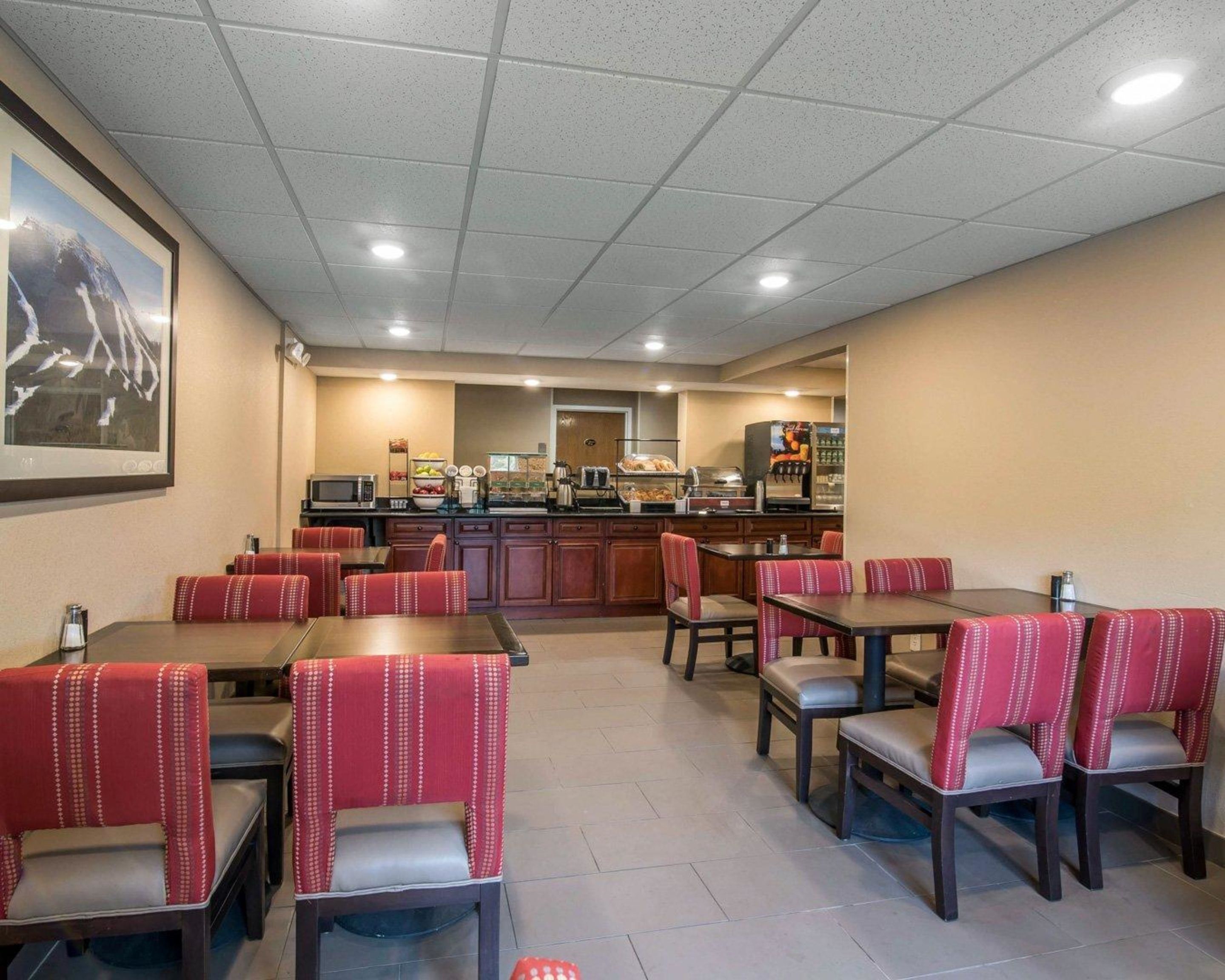 A hotel dining area with booths and tables, a kitchen in the background, and a framed picture on the wall.