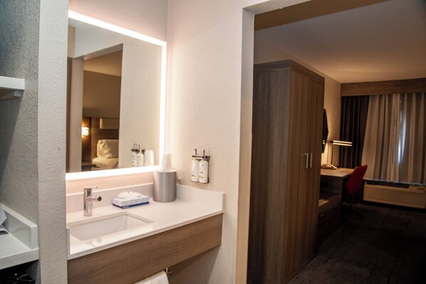 Un bagno d'albergo con lavandino, specchio e articoli da toilette.