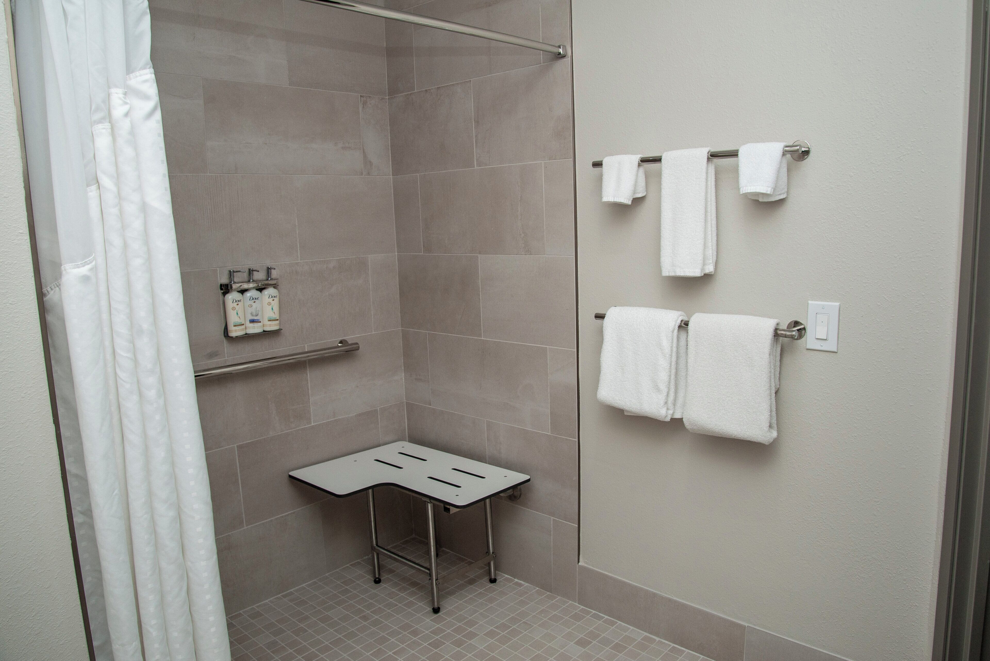 Une salle de bain avec une douche, une petite table et plusieurs serviettes rangées sur un porte-serviettes.
