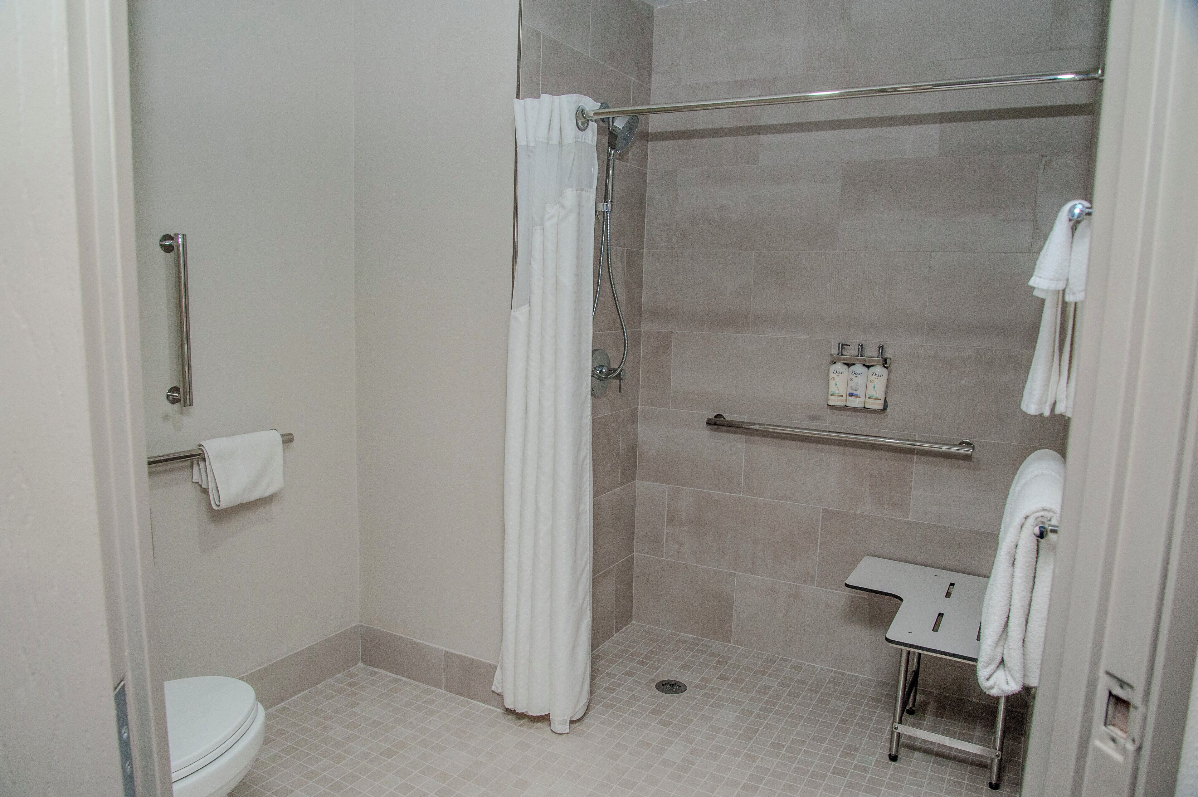 Une petite salle de bain moderne équipée d’une douche, de toilettes et d’un porte-serviettes.
