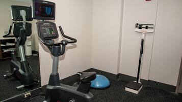 A gym with an exercise bike, a treadmill, and a mirror.