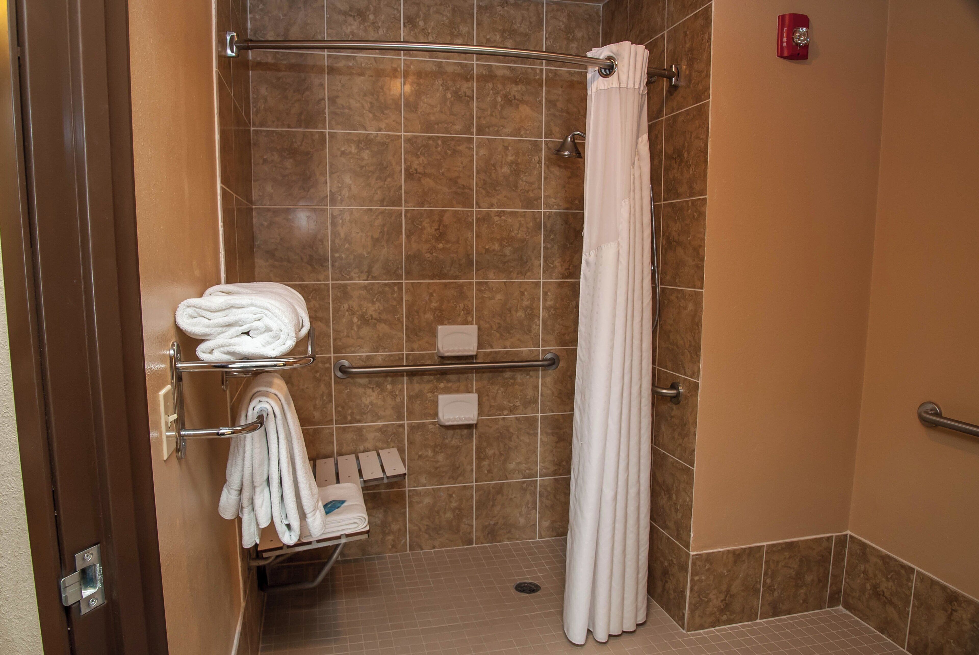 A shower area with a glass door, a towel rack with folded towels, and a shower curtain.