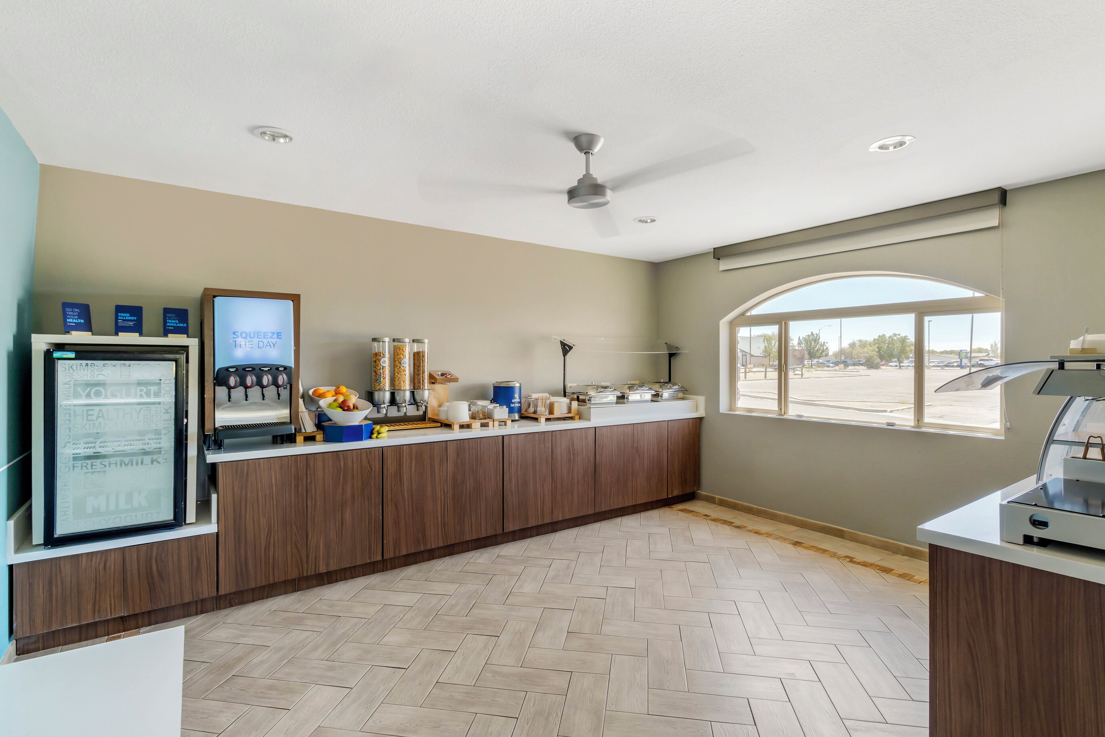 A modern kitchen with a built-in refrigerator, a coffee machine, and a window providing a view of the parking lot.
