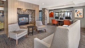 A modern lounge area with a fireplace, comfortable seating, and a stone accent wall.
