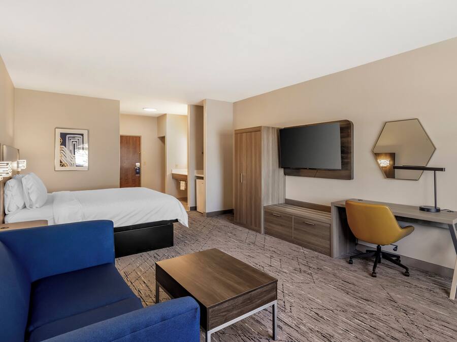 Une chambre d’hôtel avec un lit, un bureau, une chaise, une télévision et une lampe.