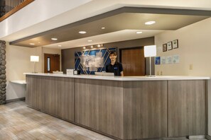 A reception desk with a modern design, a stone accent wall, and a wooden floor.