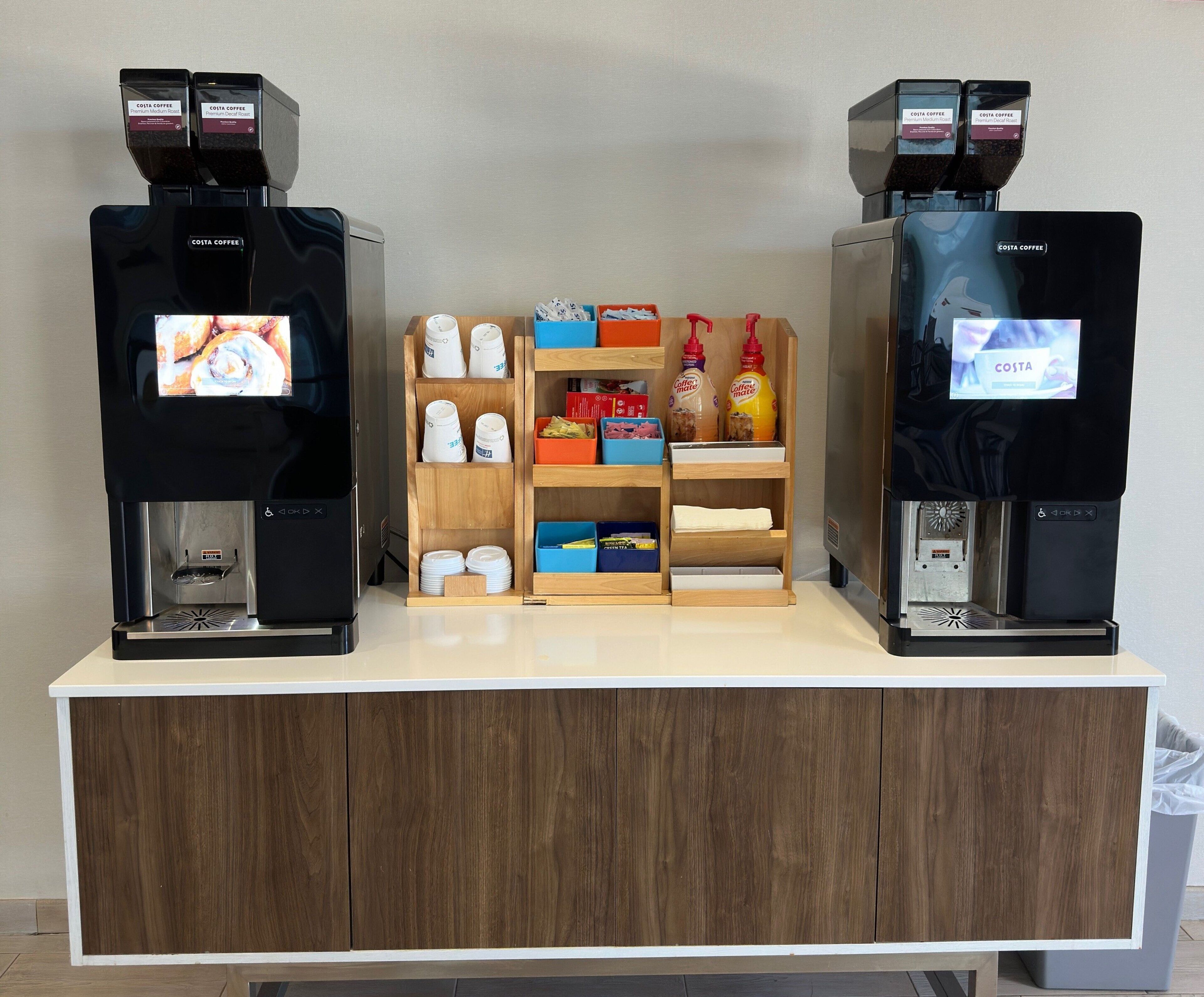 Zona de cafè amb dues màquines de cafè, una selecció de càpsules de cafè i una estanteria amb articles relacionats amb el cafè.