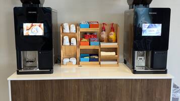 Zona de cafè amb dues màquines de cafè, una selecció de càpsules de cafè i una estanteria amb articles relacionats amb el cafè.