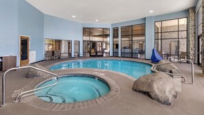 An indoor swimming pool with clear water, surrounded by stone walls and a blue ceiling.