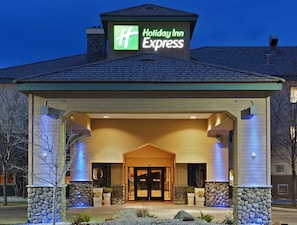 Ein Holiday Inn Express Gebäude mit einer Steinfassade, einem überdachten Eingang und einem Schild über dem Eingang.