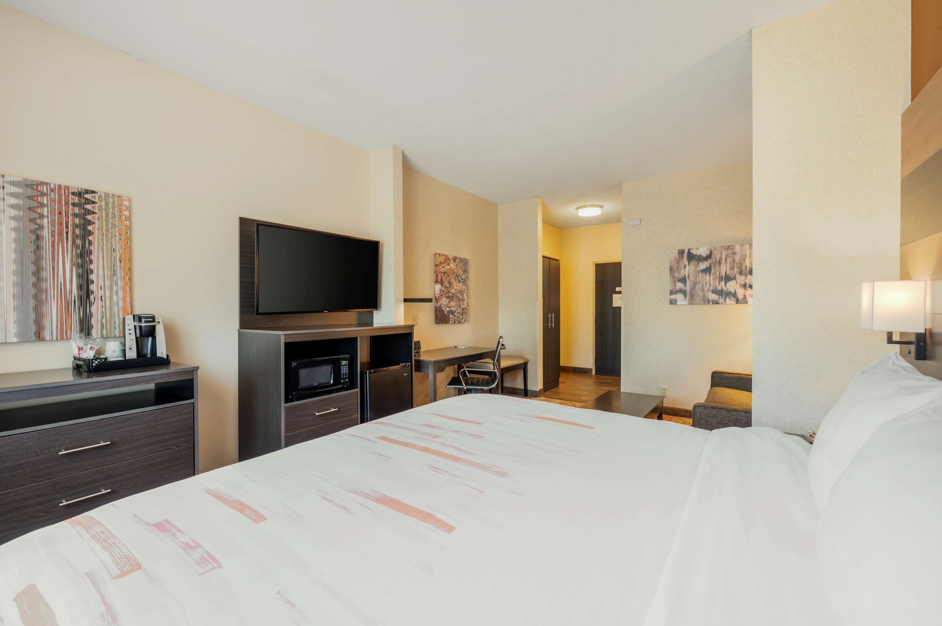 A hotel room with a bed, a desk, a television, and a coffee machine.