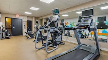 Une salle de sport équipée de tapis de course, d’appareils elliptiques et de vélos d’exercice.