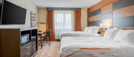 Ein Hotelzimmer mit zwei Betten, einem Schreibtisch mit Stuhl, einem Flachbildfernseher, einer Mikrowelle und einer Klimaanlage.