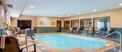 Piscina interior con sillones de descanso y vestuario.