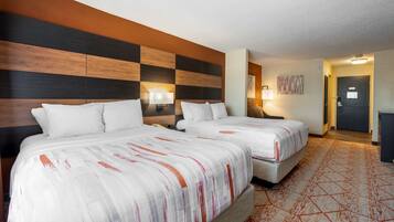 Habitación de hotel con dos camas, un gran diseño mural y una alfombra estampada.