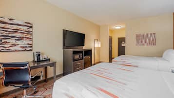 Una habitación de hotel con cama, escritorio, silla, televisión, microondas y cafetera.