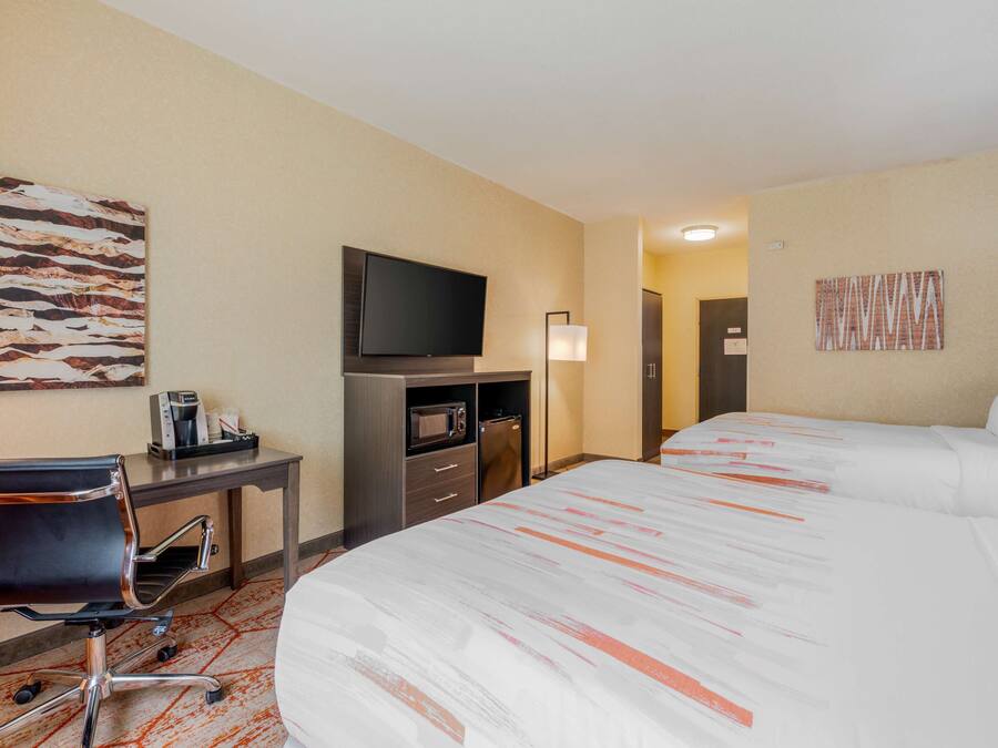 Una habitación de hotel con cama, escritorio, silla, televisión, microondas y cafetera.