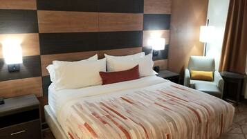 Een hotelkamer met een groot bed, twee nachtkastjes, een stoel en een lamp.