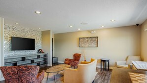A modern living room with a flat-screen TV, patterned chairs, a coffee table, and a chessboard. - Best Western Plus Warsaw (Warsaw)