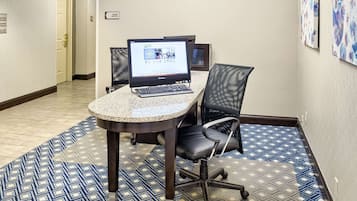 Une salle de conférence avec un ordinateur portable posé sur une table, une chaise et un tapis à motifs.