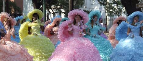 Un desfile con participantes que lucen vestidos coloridos con volantes y sombreros grandes.